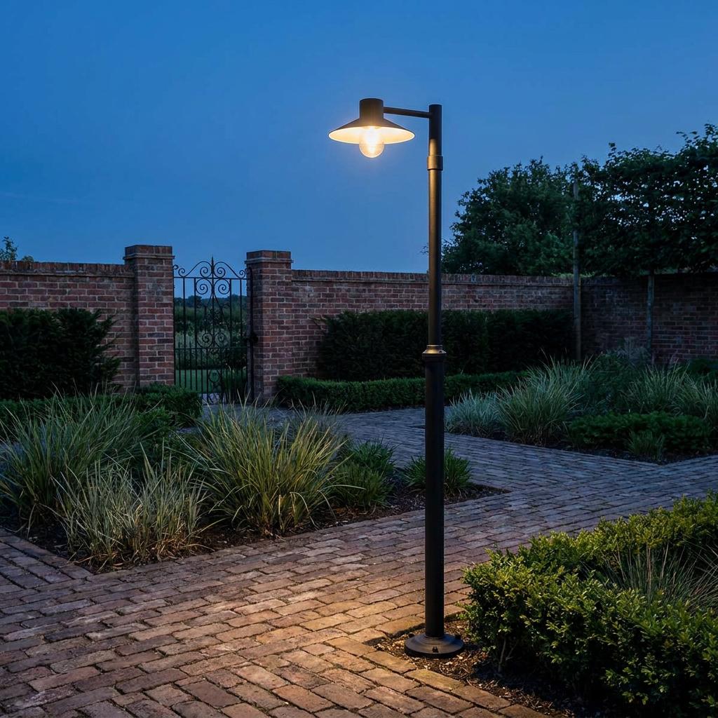 Norlys Lund black outdoor lamp post illuminating a brick garden path at dusk.