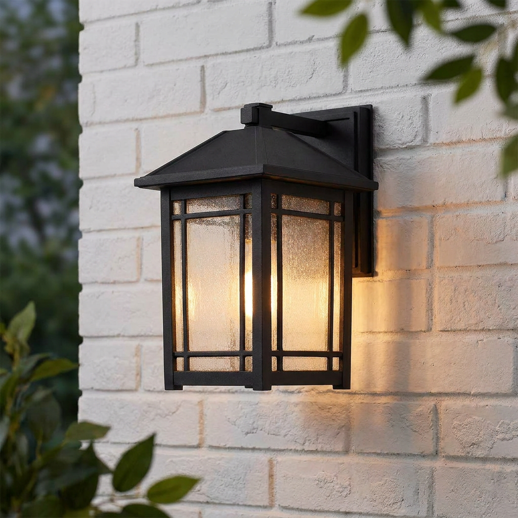Black lantern-style outdoor wall light with seeded glass panels mounted on a white brick wall.