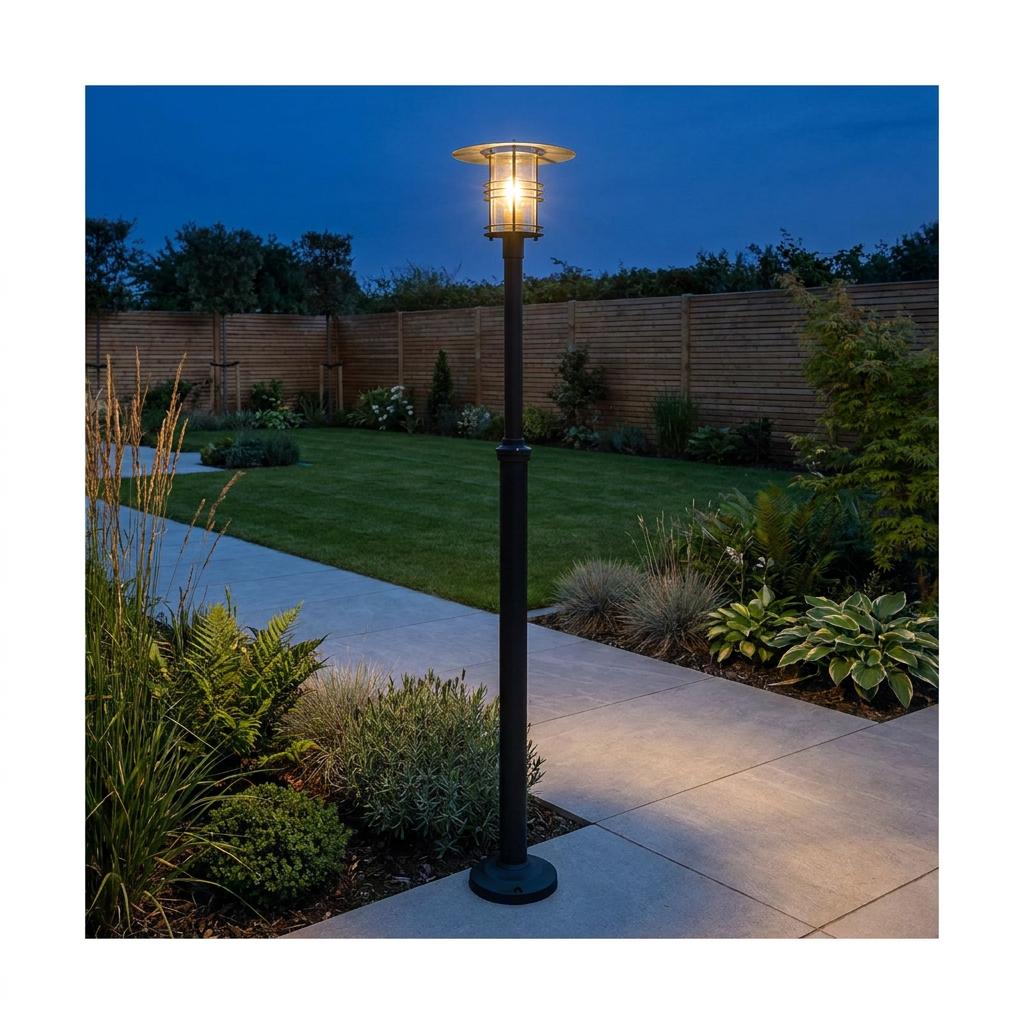 Black lantern lamp post illuminating a stone garden path and lawn at dusk.