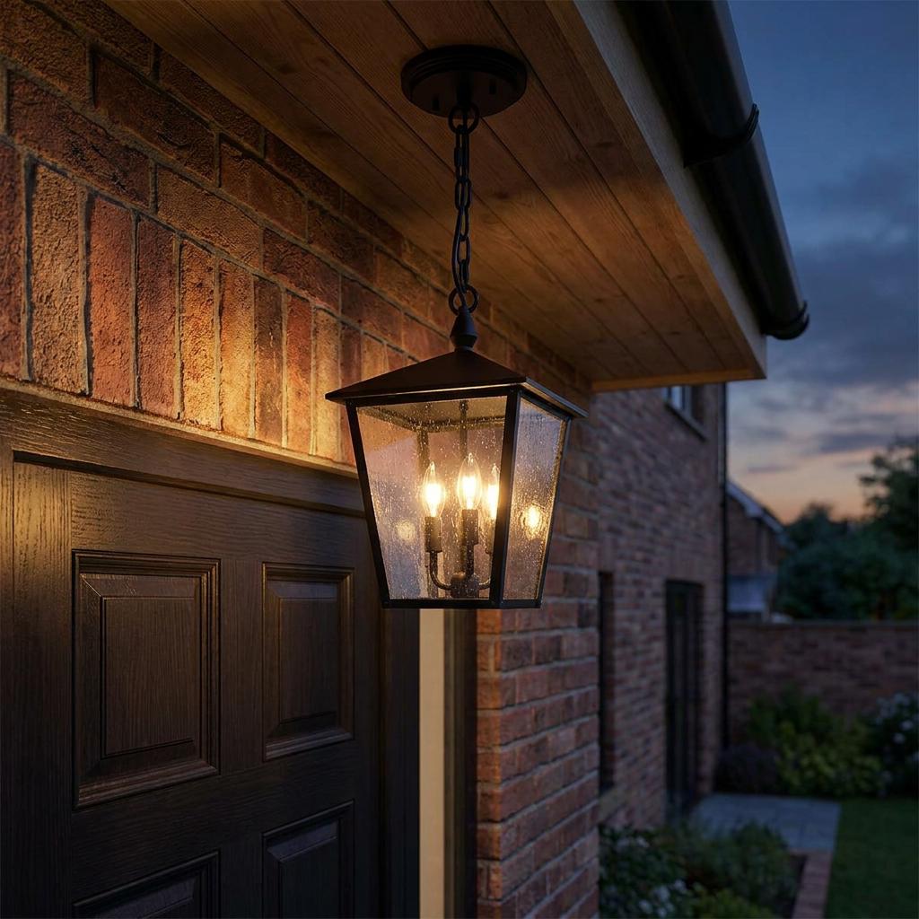 A black 3-light outdoor lantern with seeded glass hangs under a wooden porch, illuminating a brick wall at dusk.