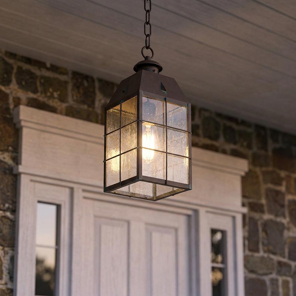 Nantucket 1 light medium brass outdoor chain lantern hanging from a porch ceiling with seeded glass panels.