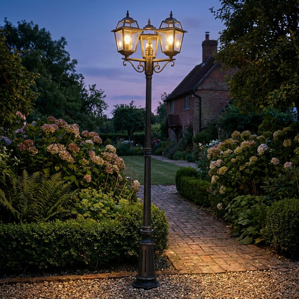 Traditional three-light black and gold outdoor post lantern illuminating a lush garden path at dusk.